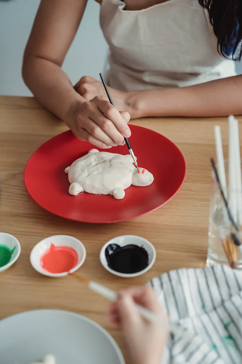 An adult and a child paint a salt-dough turtle together.